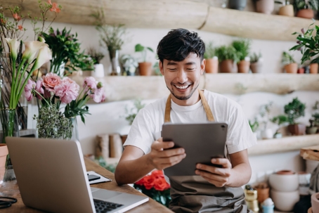Male with apron checking his tablet and laptop