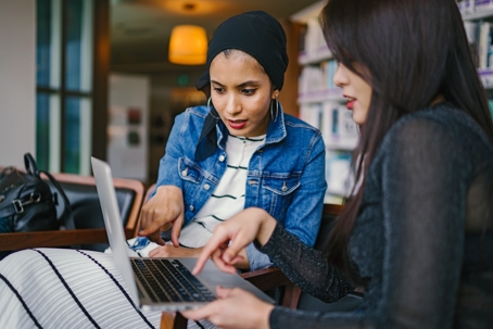 two employees sitting in office pointing at laptop